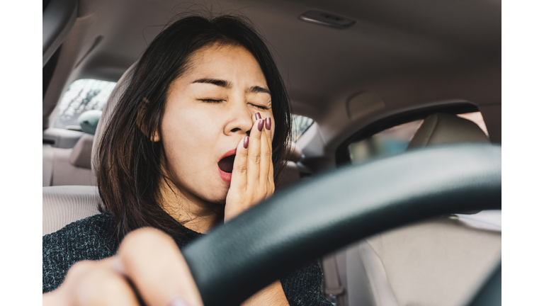 Tired sleepy Asian woman yawning during driving car