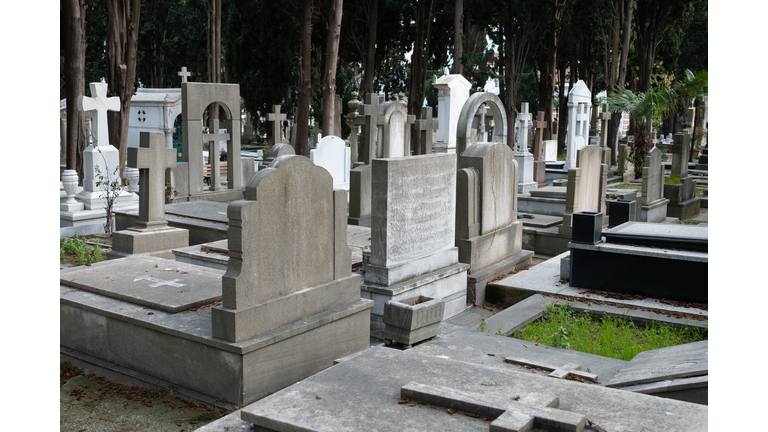 The city cemetery with old unkempt graves. Stone tombstones, metal crosses. City cemetery. Gravestones and stone crosses, abandoned and overgrown with grass graves of unknown people. The concept of death, the end of life, sadness, sorrow and loneliness.