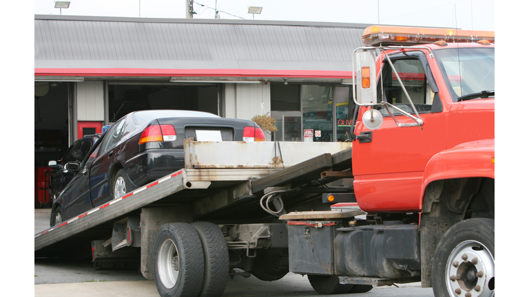 Black car on a red flat bed tow truck