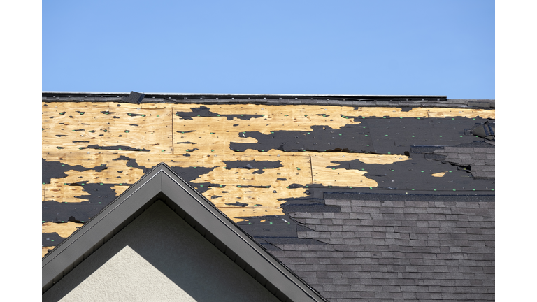 Damaged house roof with missing shingles after hurricane Ian in Florida. Consequences of natural disaster