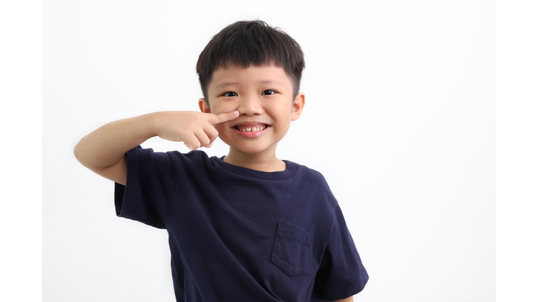 Portrait of cute little asian boy pointing his nose, isolated on white background