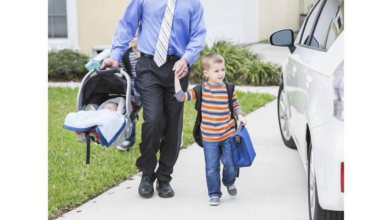 Businessman with baby taking son to school