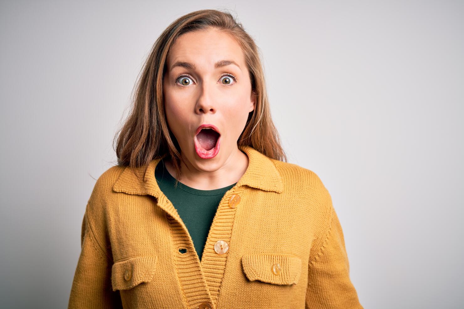 Young beautiful blonde woman wearing casual sweater over isolated white background afraid and shocked with surprise expression, fear and excited face.