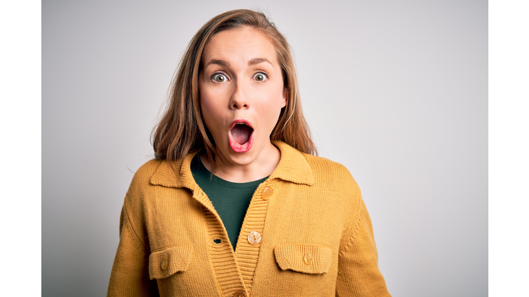 Young beautiful blonde woman wearing casual sweater over isolated white background afraid and shocked with surprise expression, fear and excited face.