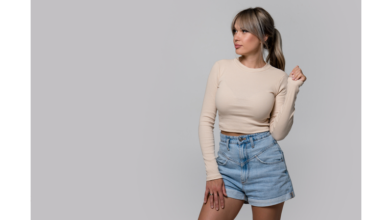 Woman in beige long sleeve and shorts on light background