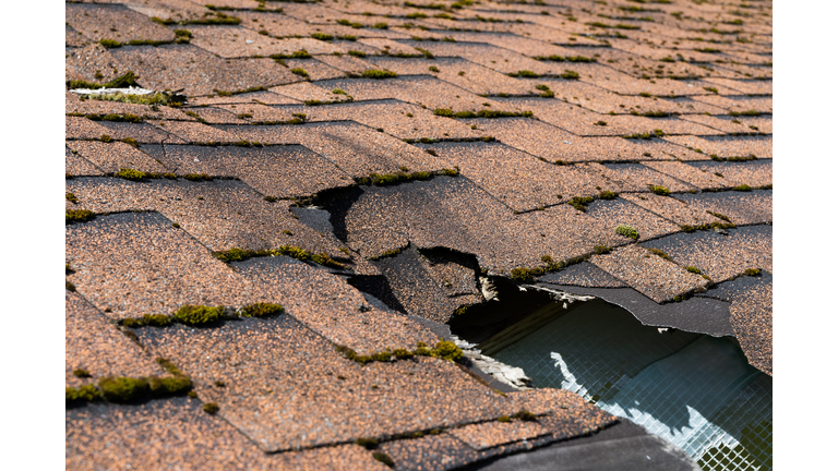 Close up view of asphalt shingles roof damage that needs repair.