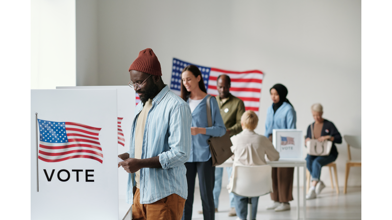 Group of young multicultural voters standing in queue in polling place