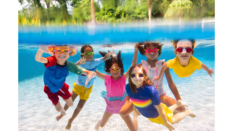 Kids jump into swimming pool. Summer water fun.