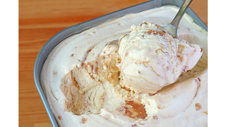 Closeup of a Spoon Scooping Delectable Caramel Macadamia Nut Ice Cream in the tub