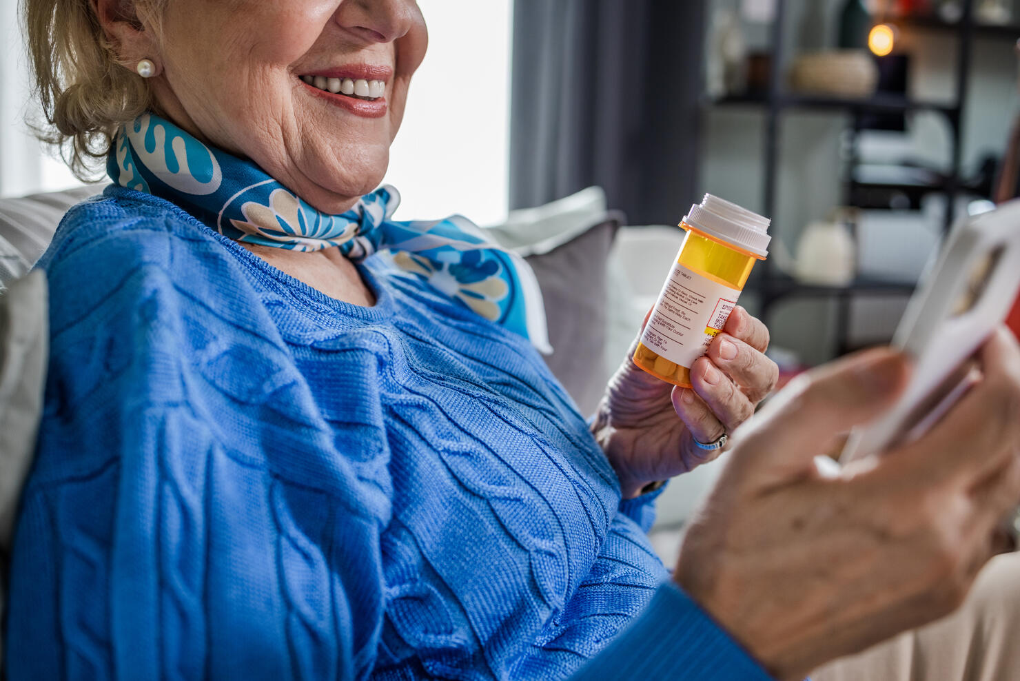 Close-up of a senior woman holding a pill bottle and a mobile phone