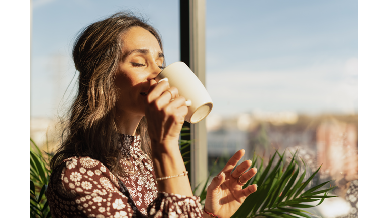 Closeup portrait of woman drinking coffee in the morning at home