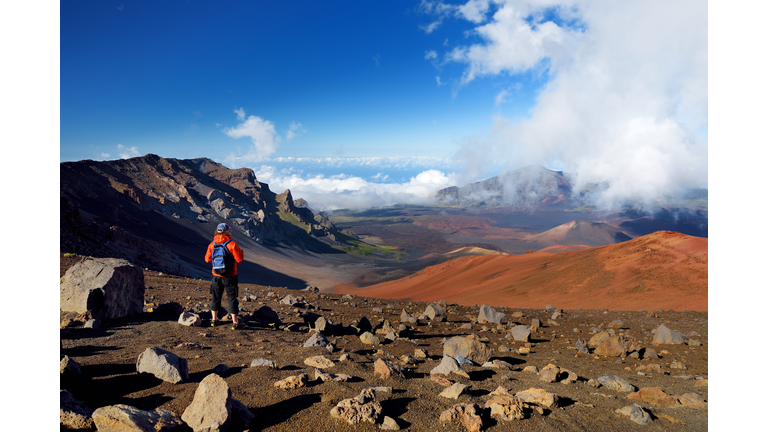 Tourist hiking in Haleakala volcano crater on the Sliding Sands trail. Beautiful view of the crater floor and the cinder cones below. Maui, Hawaii