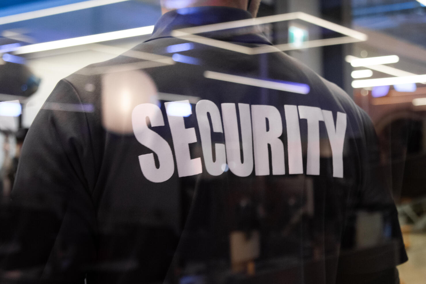 Security guard standing inside a commercial building nearby the window reflecting light