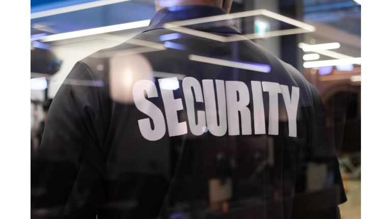 Security guard standing inside a commercial building nearby the window reflecting light