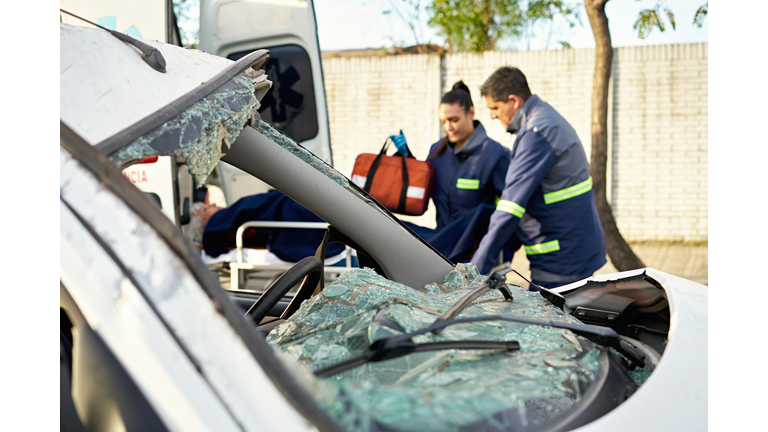 Damaged vehicle and paramedics caring for accident victim