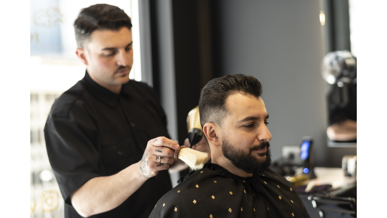 Barbershop man gets a modern shave, beard and hairstyle, using hair brush, 40s years old male beauty