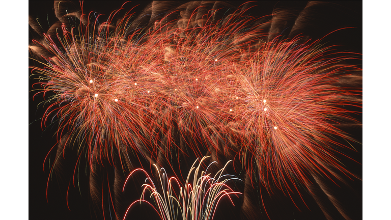 Long exposure of the colorful light trails of rockets and firecrackers of a night fireworks display against a black sky background