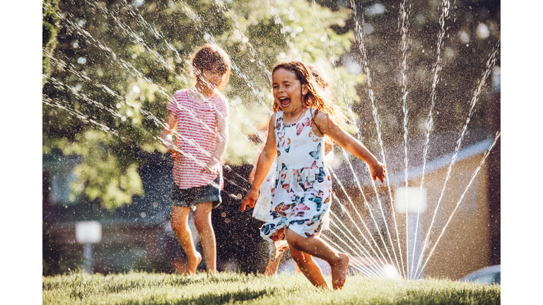 Happy kids playing with garden sprinkler