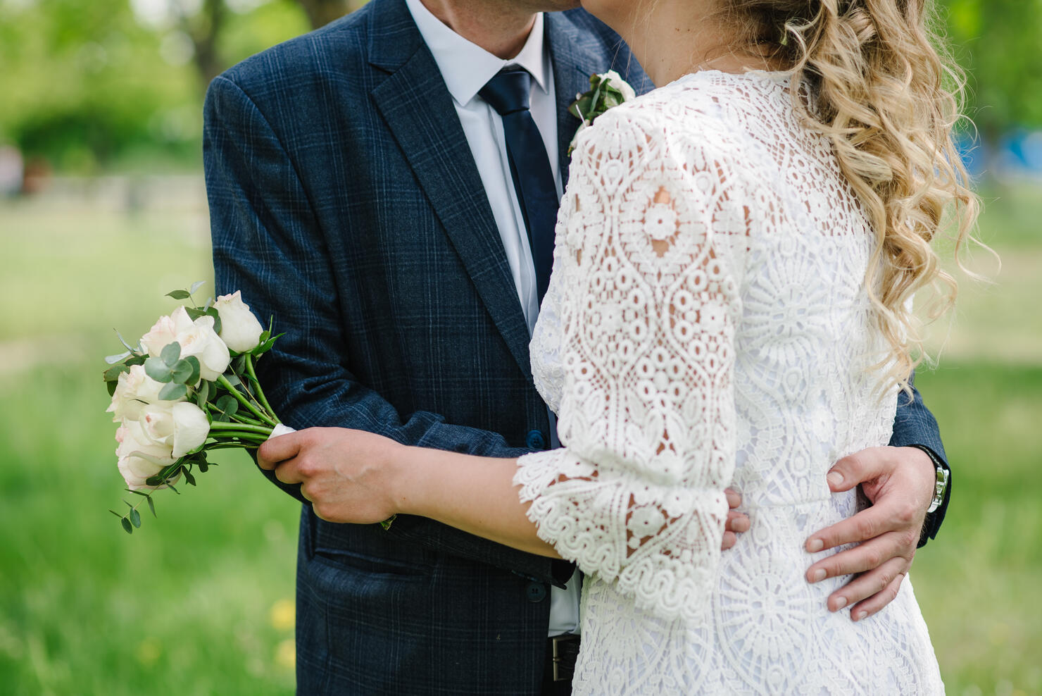 Amazing wedding couple. Romantic wedding moment, newlyweds in nature in the park. The bride holds a wedding bouquet. Close up.