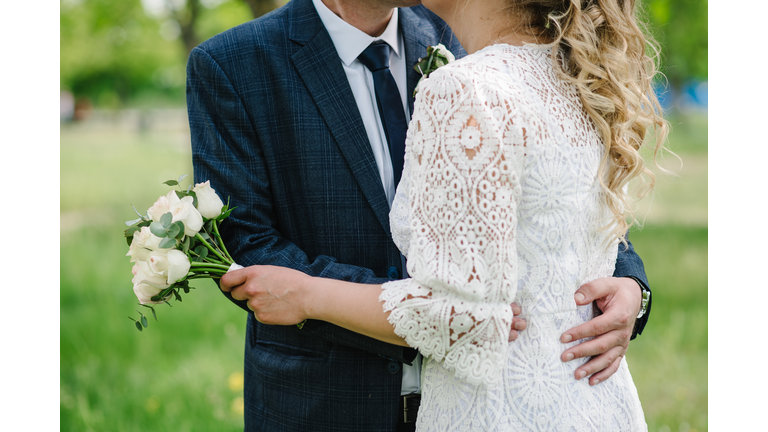 Amazing wedding couple. Romantic wedding moment, newlyweds in nature in the park. The bride holds a wedding bouquet. Close up.