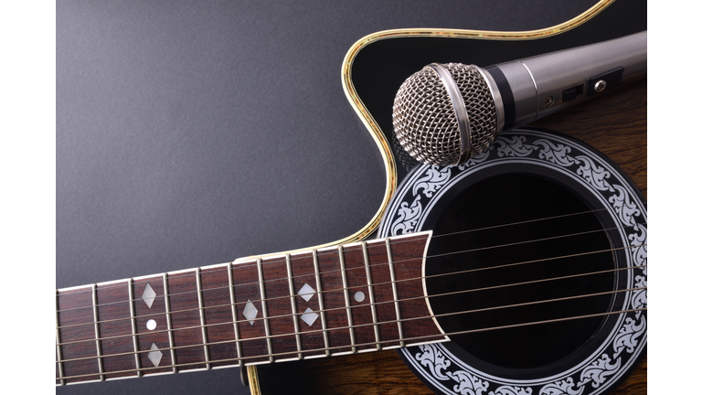 Acoustic guitar and microphone isolated on black table top