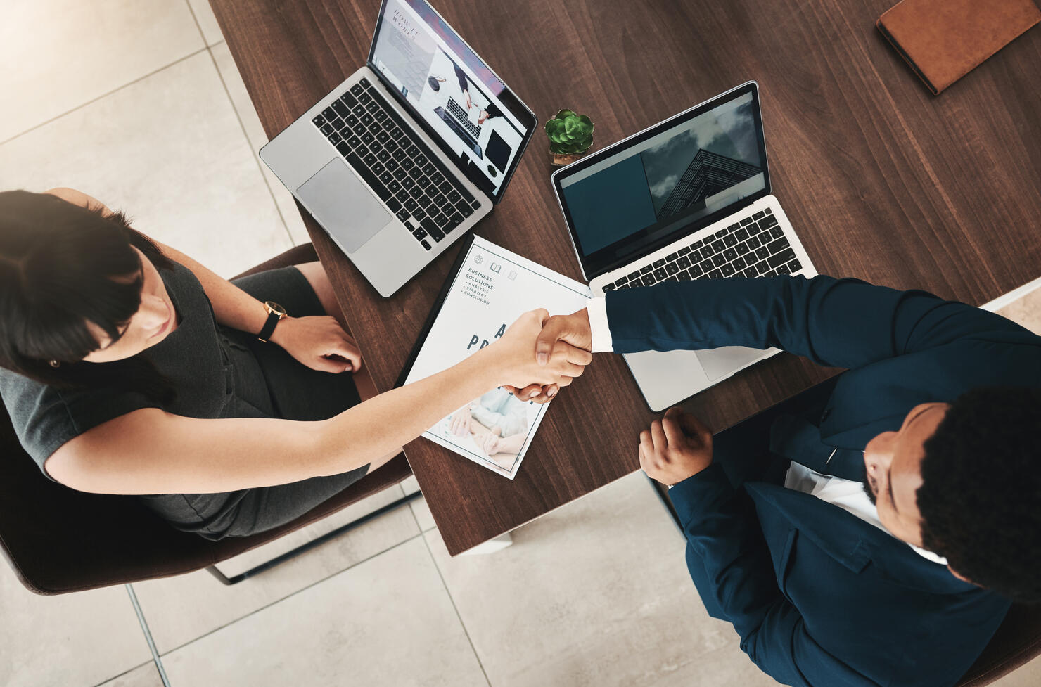 Top view, handshake and partnership of business people in office for contract, deal or onboarding. Thank you, welcome and man and woman shaking hands for hiring, recruitment or teamwork, b2b or crm