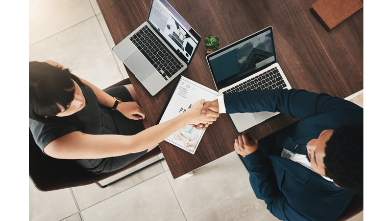 Top view, handshake and partnership of business people in office for contract, deal or onboarding. Thank you, welcome and man and woman shaking hands for hiring, recruitment or teamwork, b2b or crm