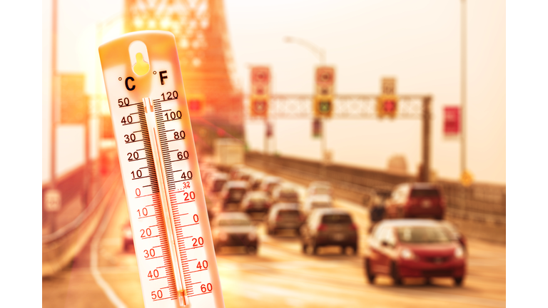 Thermometer in front of cars and traffic during heatwave