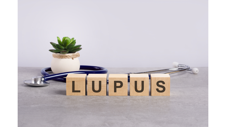 lupus word written on wooden blocks and stethoscope on light gray background