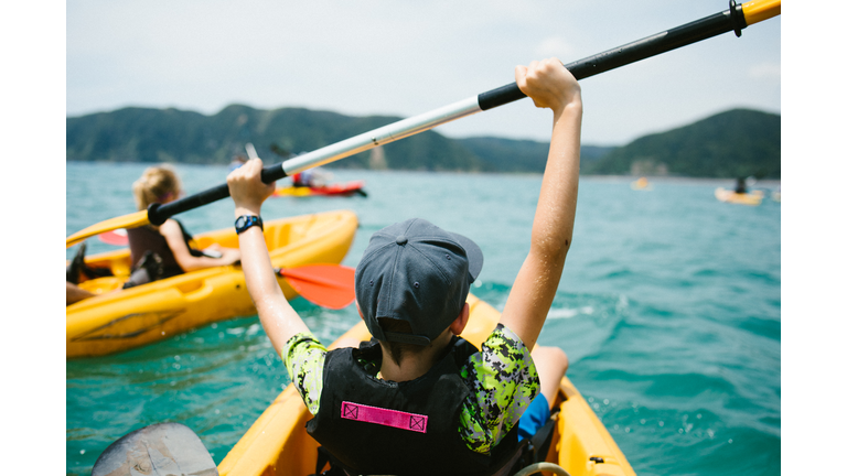 Excited boy in kayak on ocean adventure with family and group