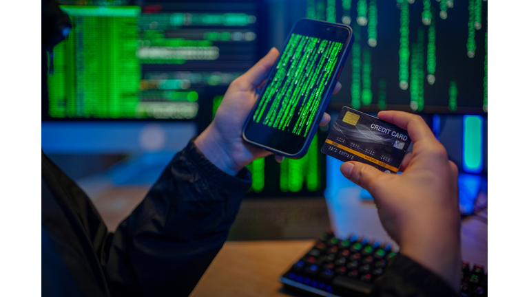 Hand of telephone scammers using a mobile phone and credit card.