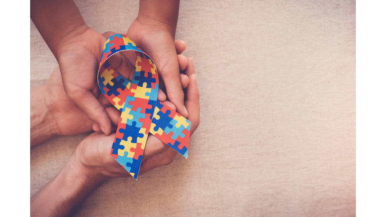 Hands holding puzzle ribbon for autism awareness