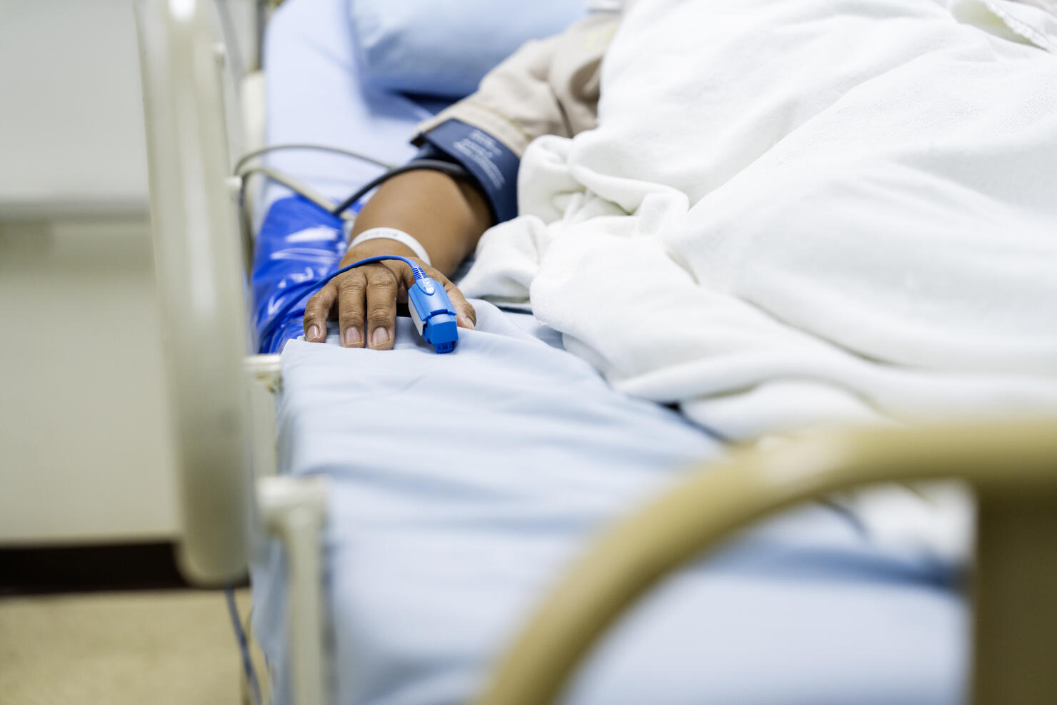 In the Hospital Sick Male Patient Sleeps on the Bed. Heart Rate Monitor Equipment is on His Finger.