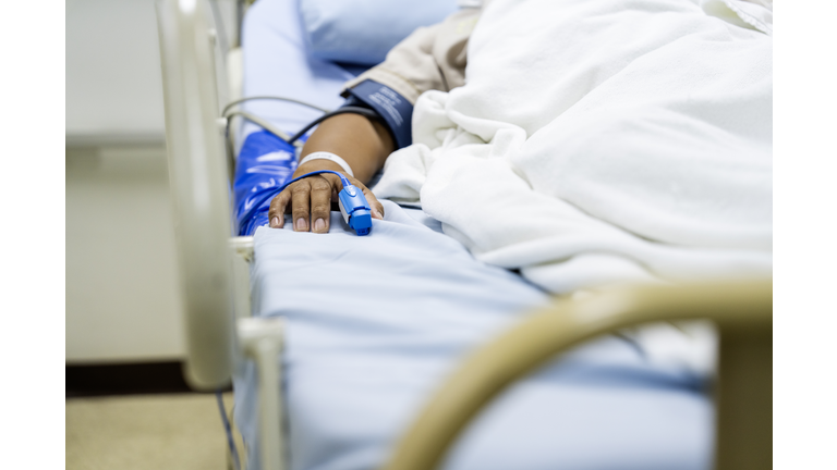 In the Hospital Sick Male Patient Sleeps on the Bed. Heart Rate Monitor Equipment is on His Finger.