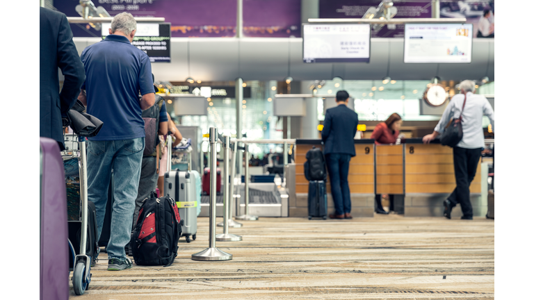 Passengers lined up at the airport to check in their luggage.