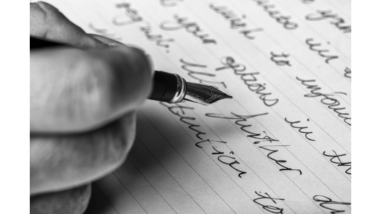 Hand writes words with a fountain pen on paper