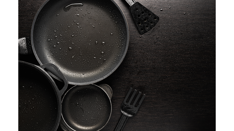 Black frying pans with a non-stick teflon coating on black background