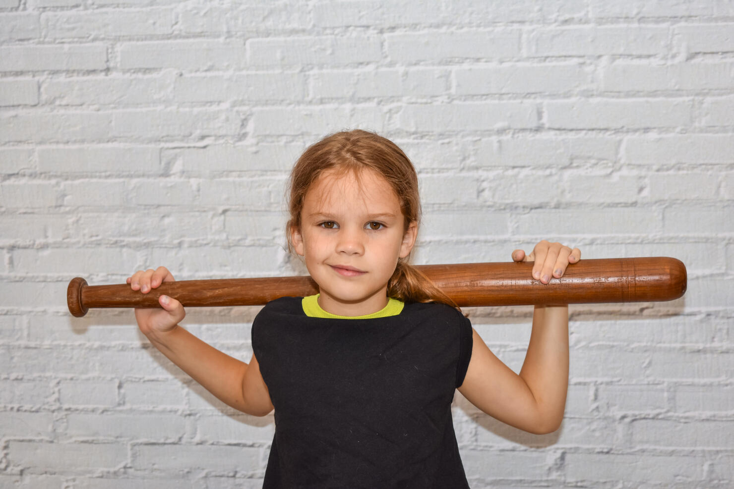 child a girl with a baseball bat plays a bully