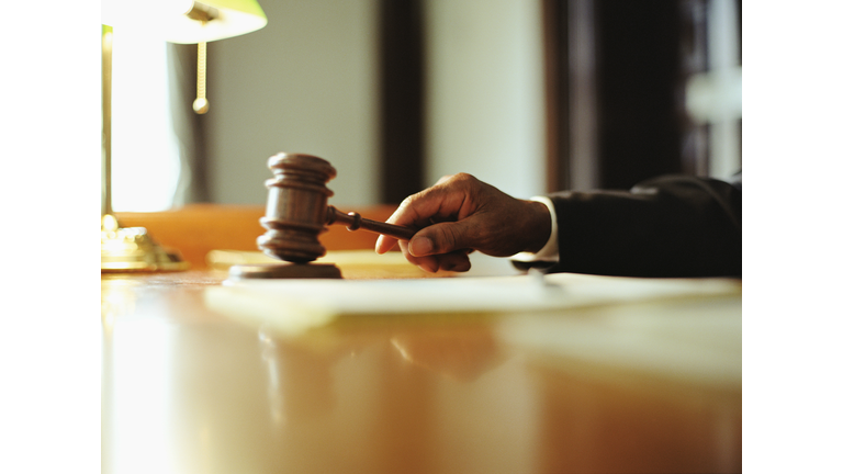 Male judge striking gavel in courtroom, close-up