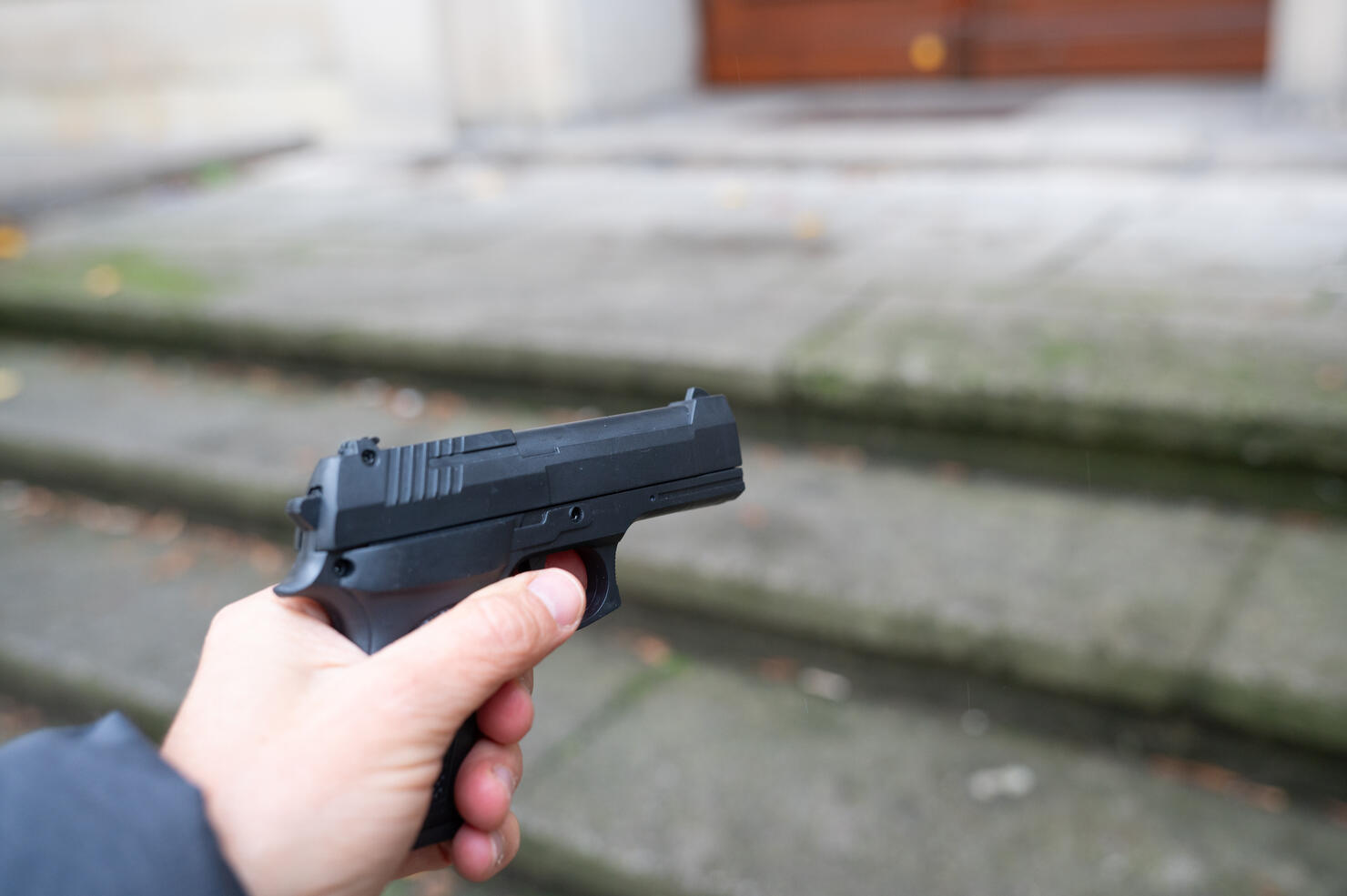 A person points a gun in one direction in a street.
