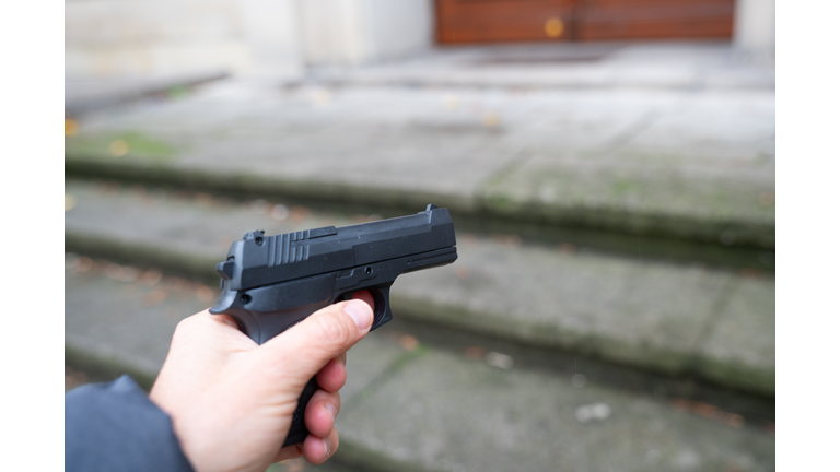 A person points a gun in one direction in a street.