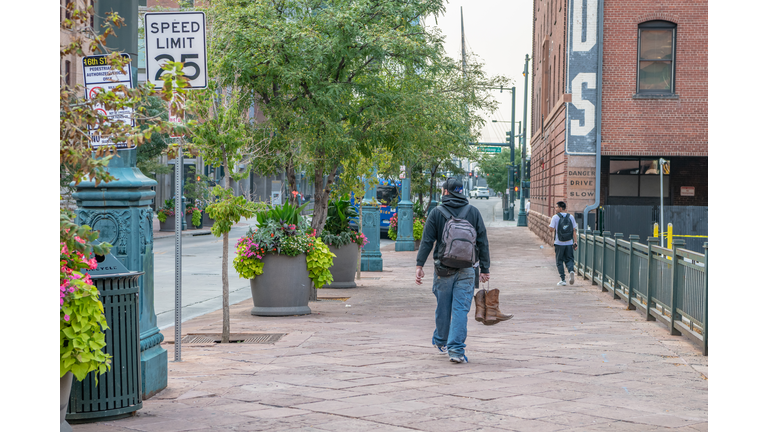 man carries cowboy boots in LoDo Denver