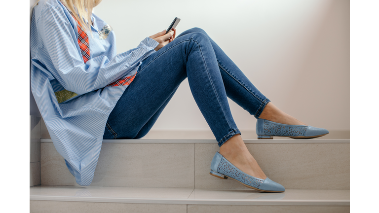 Young woman sitting on stairs and using mobile phone