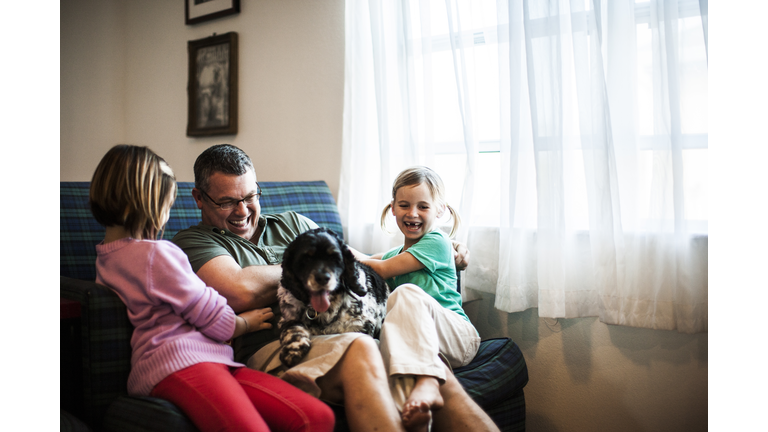 young girls playing with father and dog