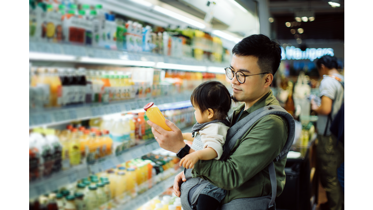 Young Asian father with cute little daughter grocery shopping for fresh fruit juice in supermarket