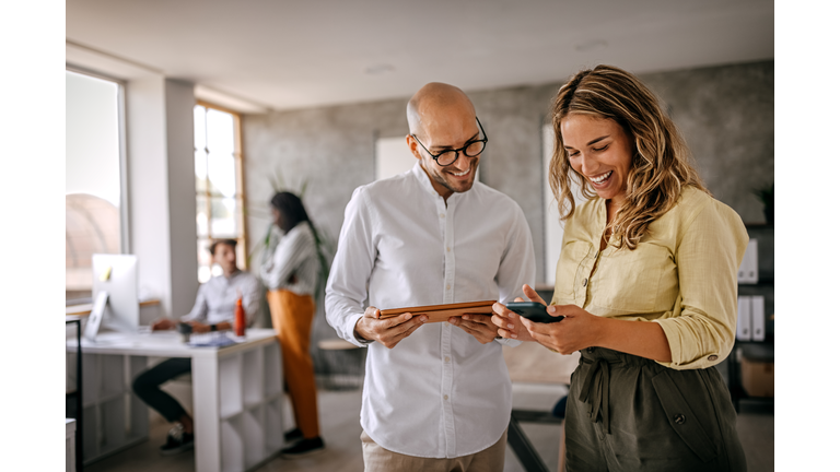 Businessman and businesswoman smiling looking at phone