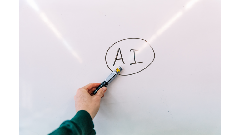 Man's hand showing a blackboard with Artificial Intelligence written on it.