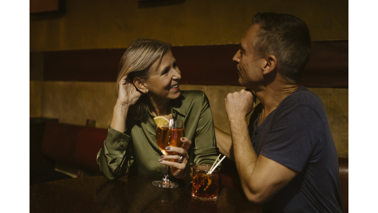 Man talking with woman holding wineglass while sitting at restaurant