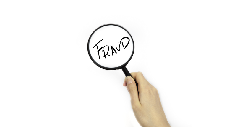 Looking though a magnifying glass onto FRAUD