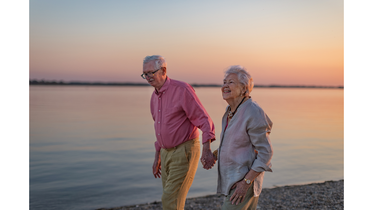 A senior couple enjoying summer vacation by the sea, celebrating their wedding anniversary.